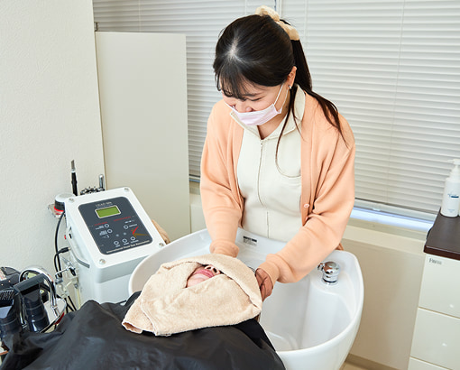 男性の患者様に薄毛治療を行う女性スタッフの様子